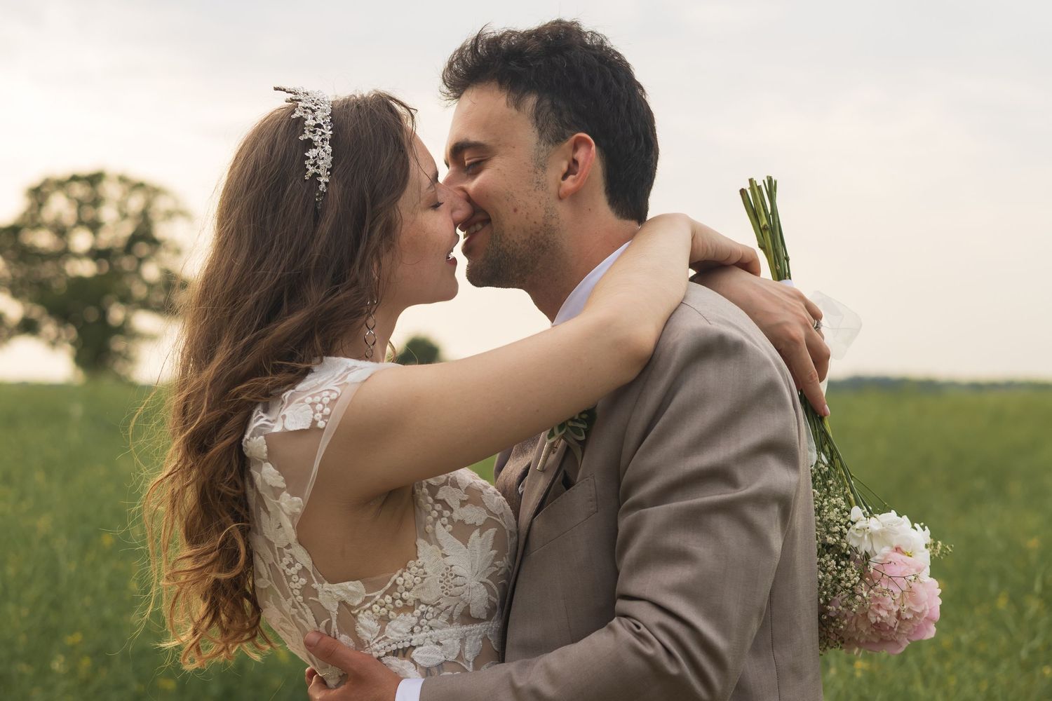 Bride and groom embracing outdoors at golden hour, peonies