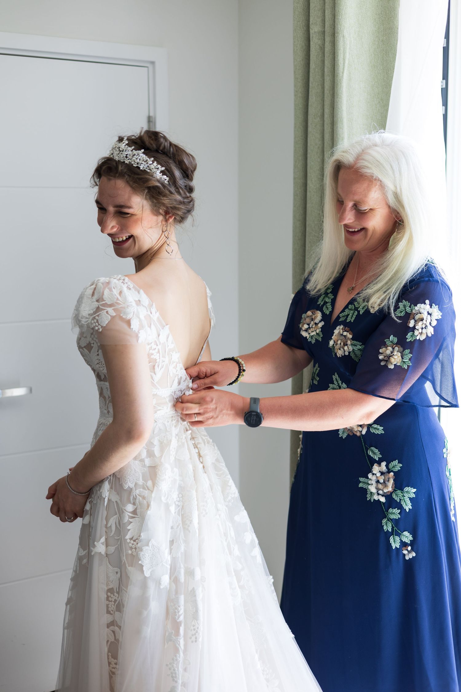 Bride being helped into her wedding dress indoors