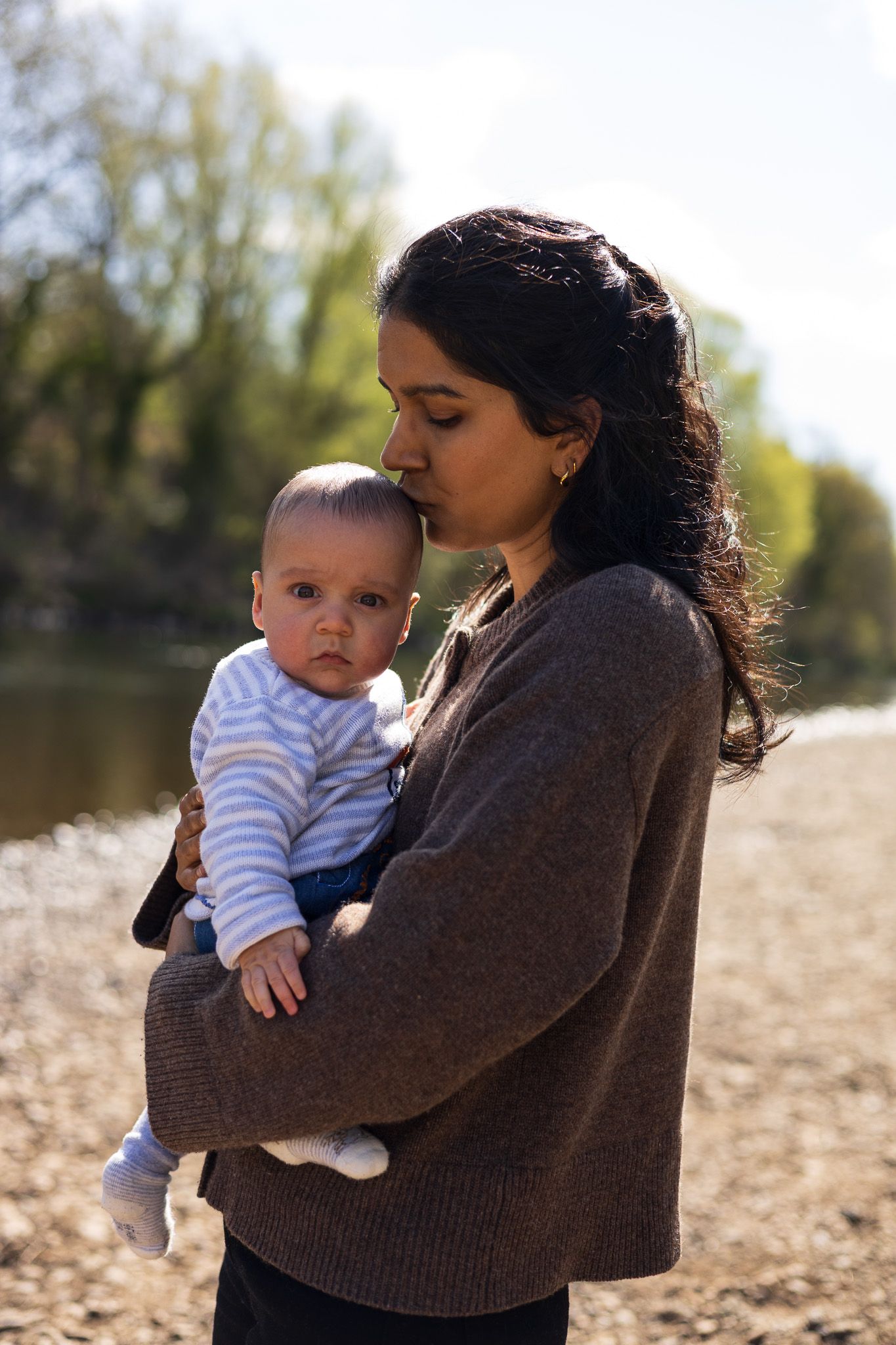 Mother holding her baby by the water during a family photoshoot