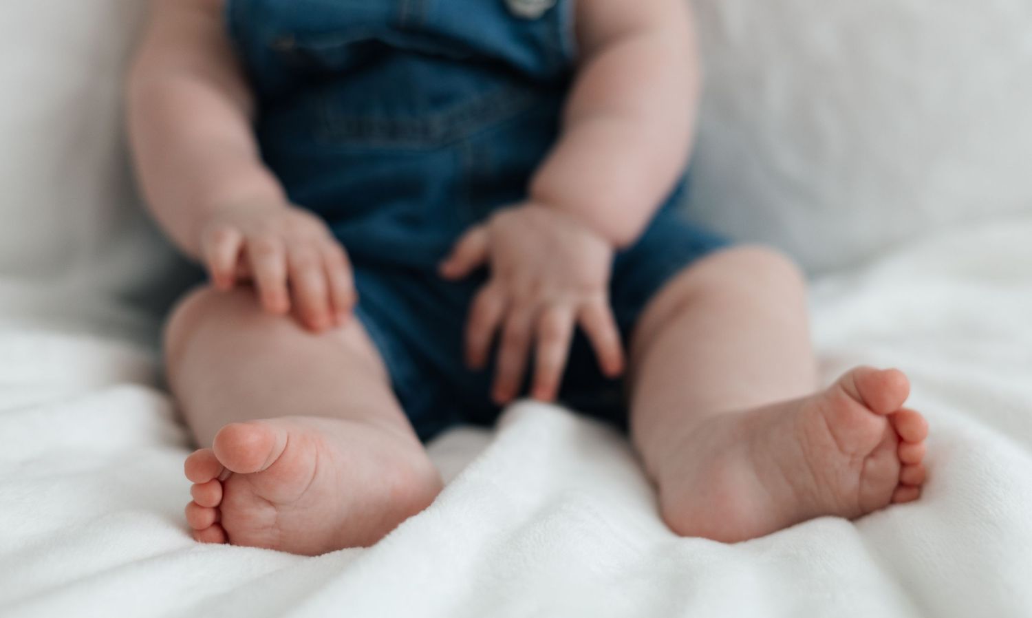 Close-up of a baby's feet and legs sitting on a soft blanket