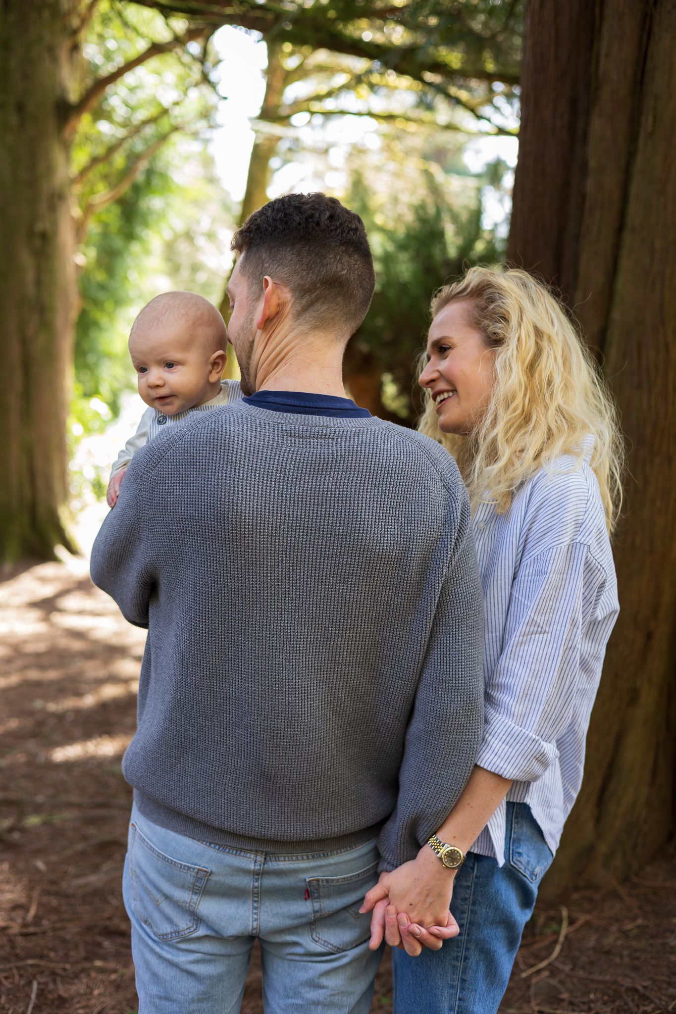 Family walking together through woodland, father carrying young child