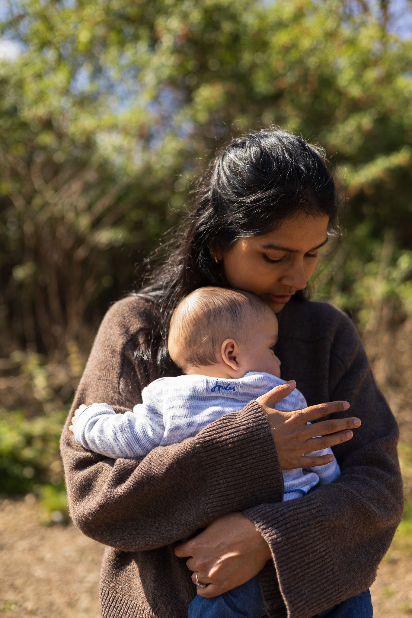 Mother holding her baby amongst trees during an outdoor family photoshoot