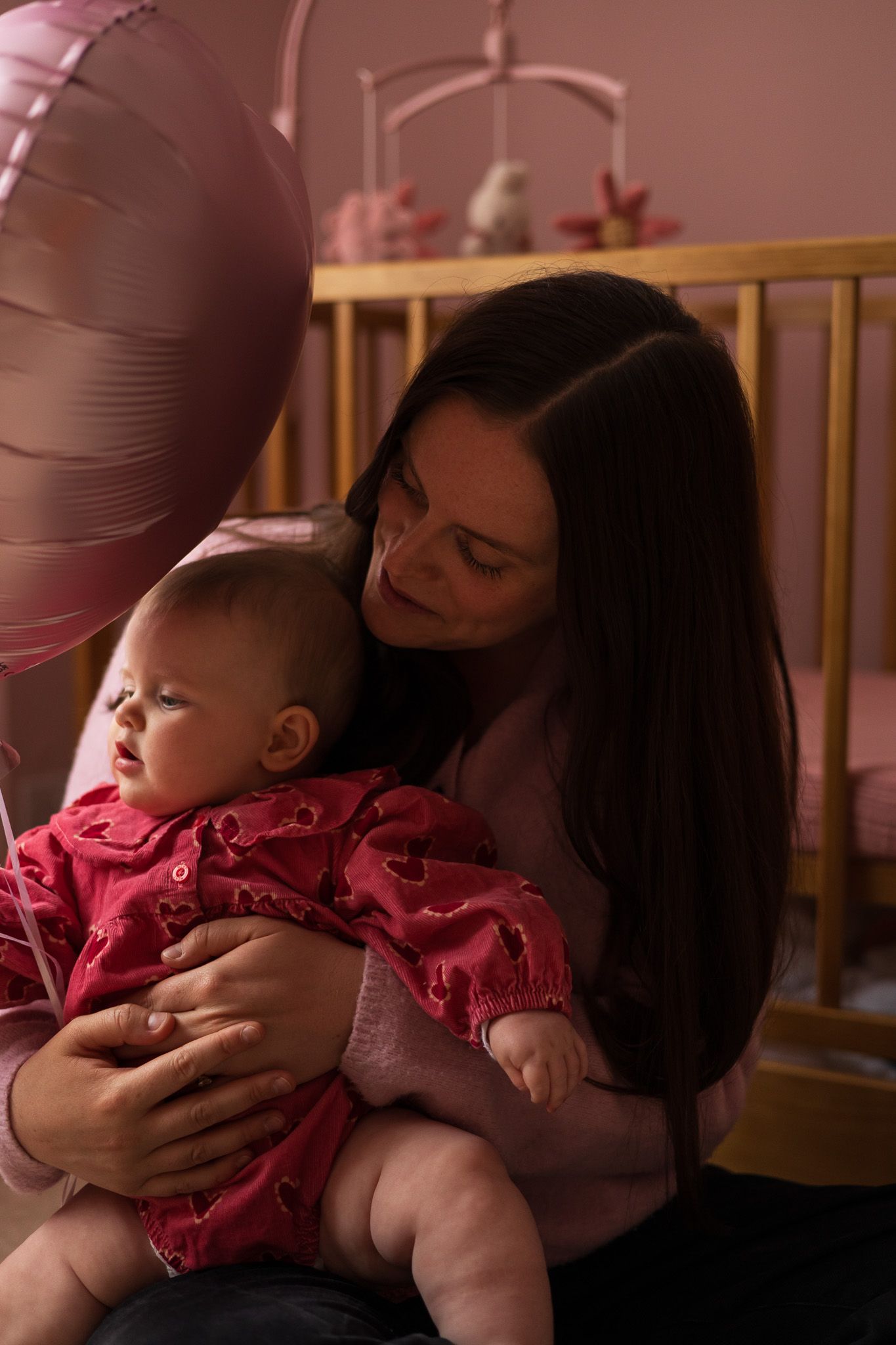 Mother kissing her baby in a pink nursery