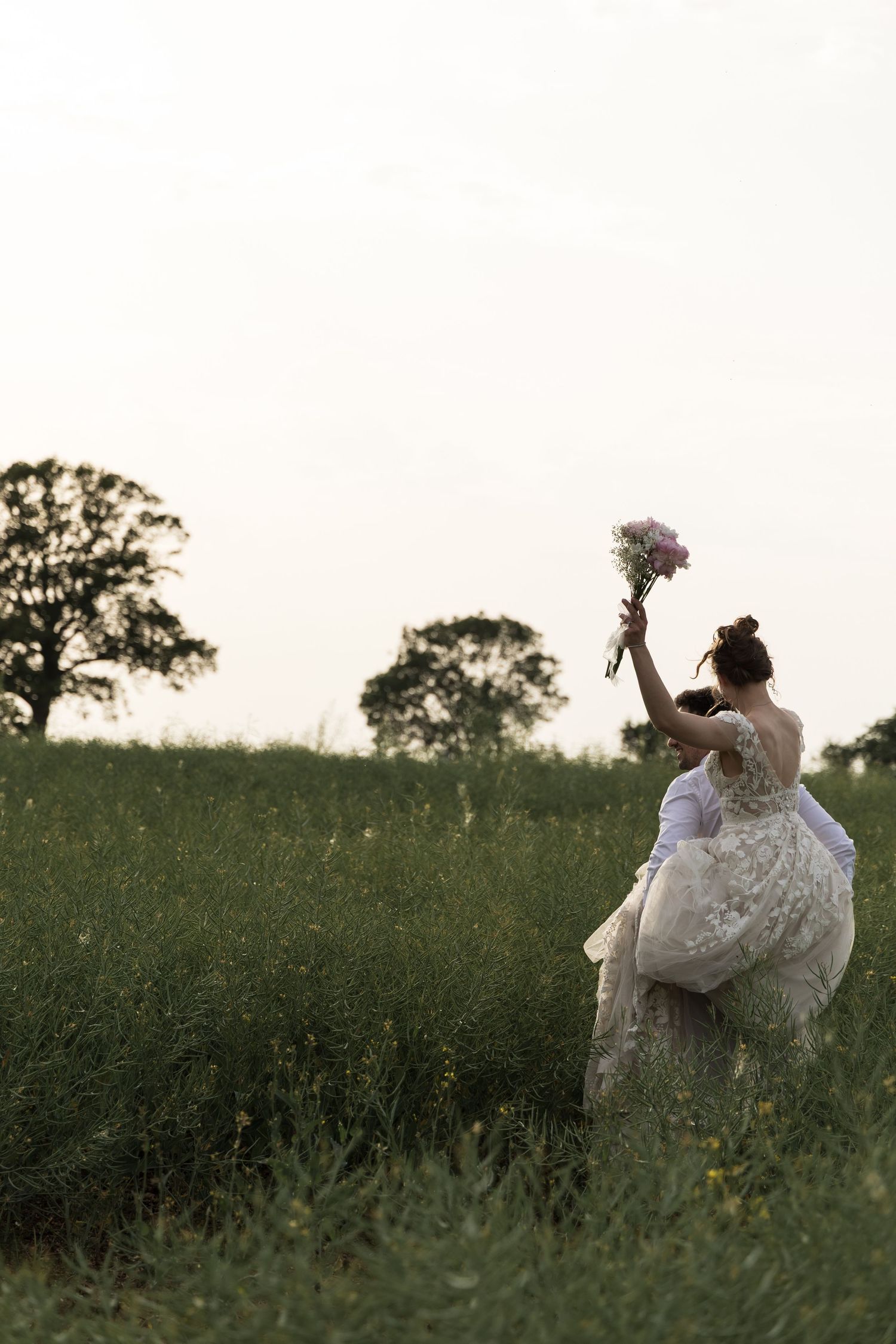Bride walking alone through a field holding her bouquet at golden hour