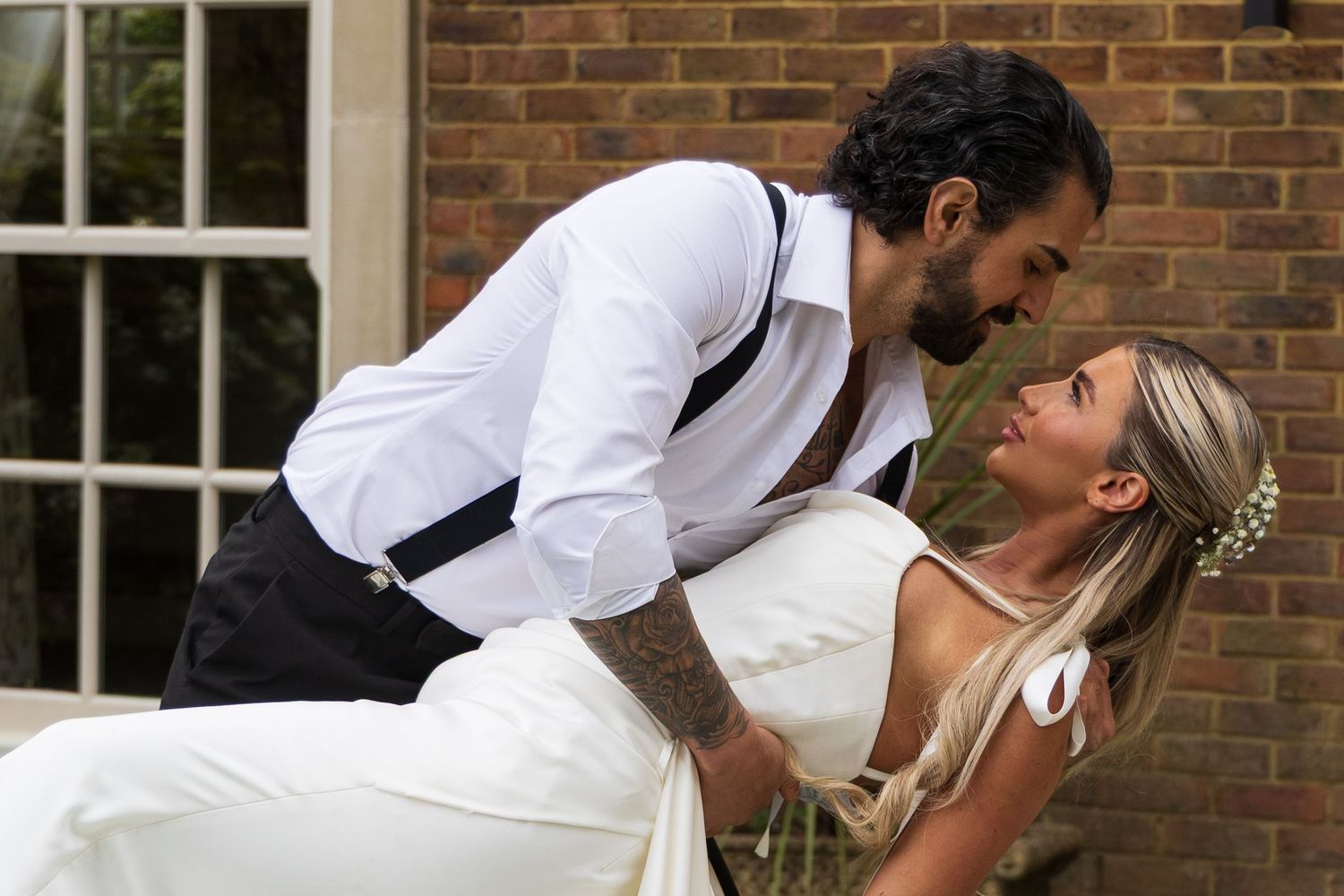 Groom leaning down to kiss his bride outside a brick building, de courceys manor