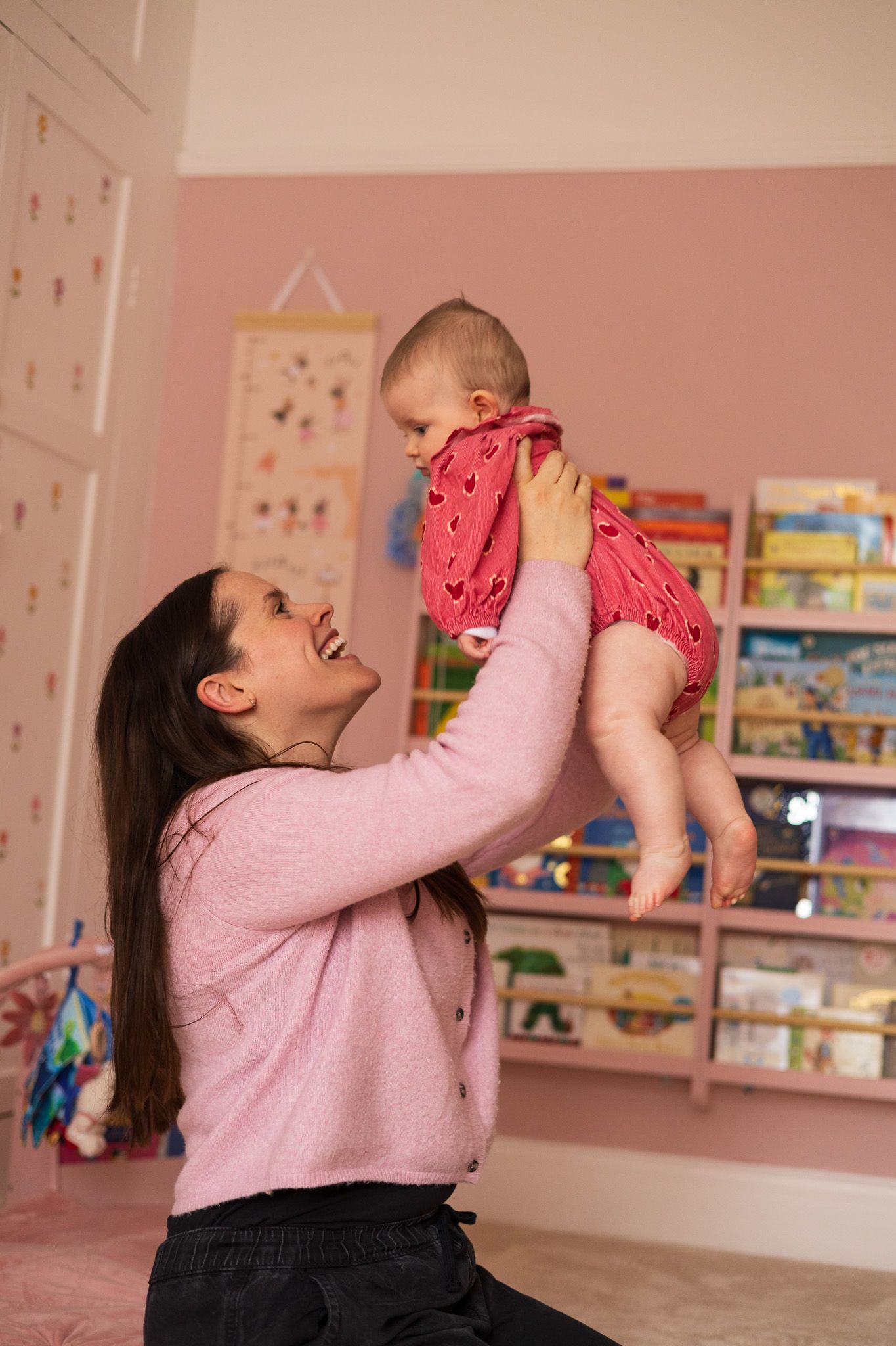 Mother lifting her baby up joyfully in the nursery