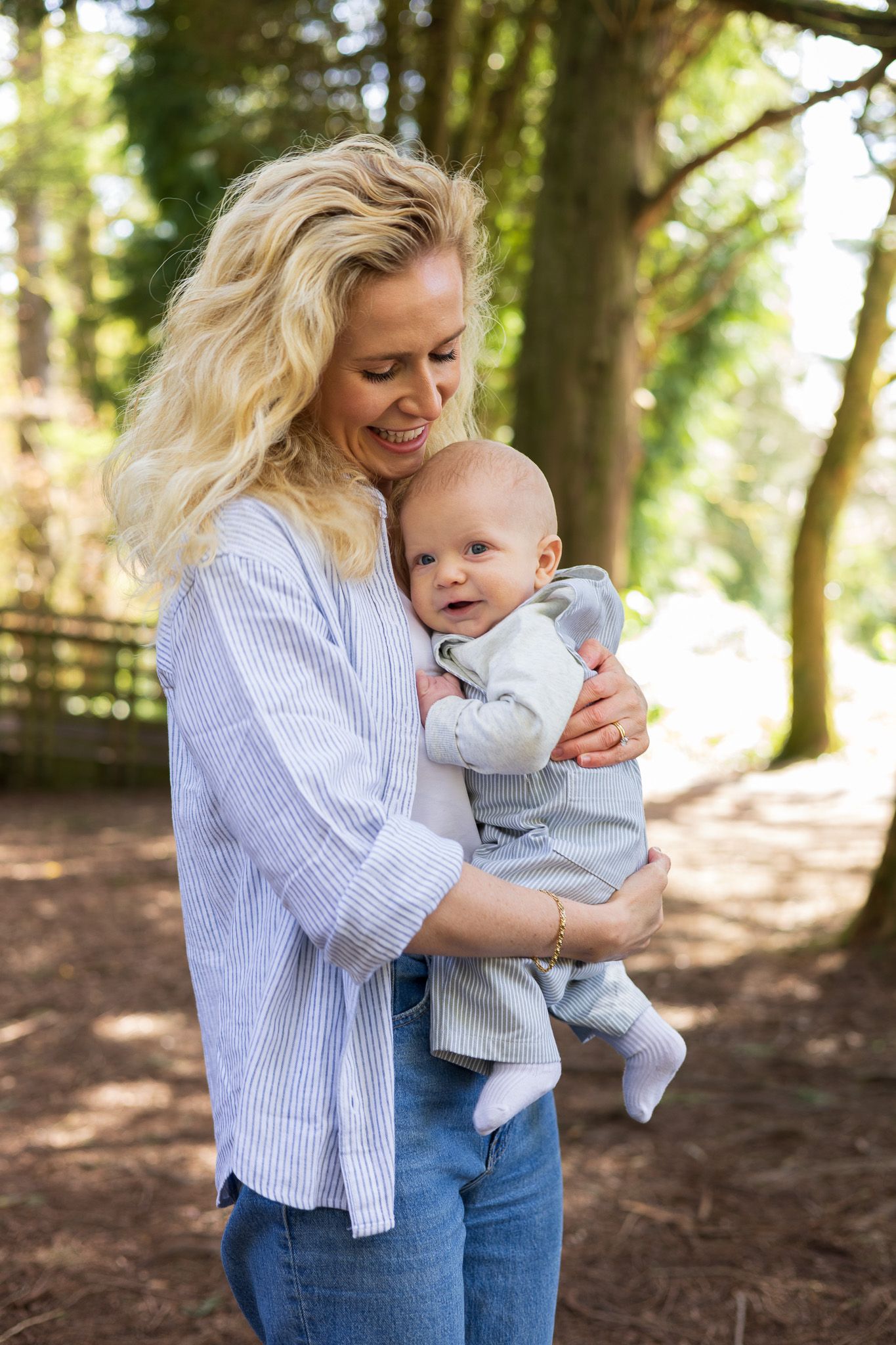 Mother holding her baby outdoors among the trees