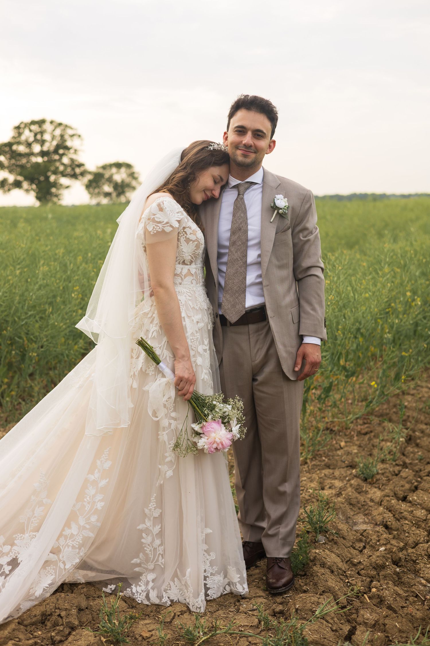 Bride and groom standing together in a field