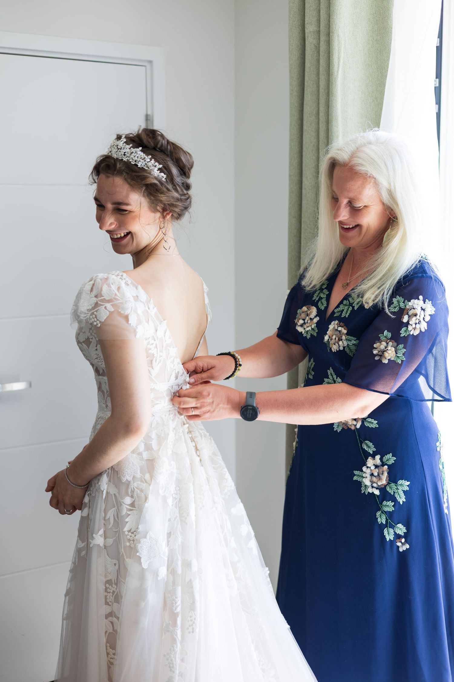 Mother helping bride get ready in her wedding dress