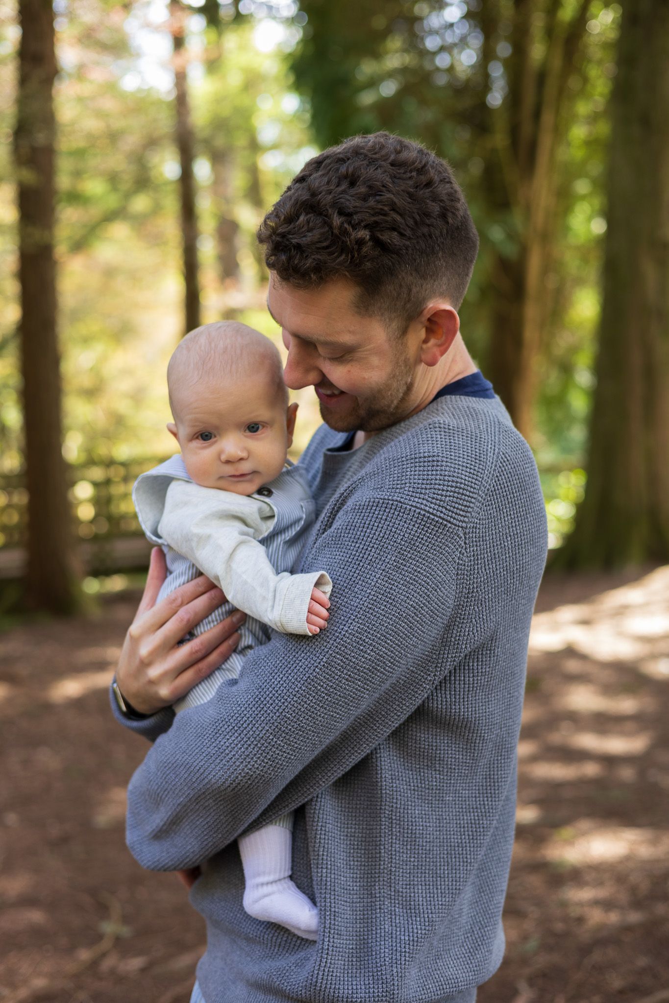 Father cradling his baby close while standing in the woods