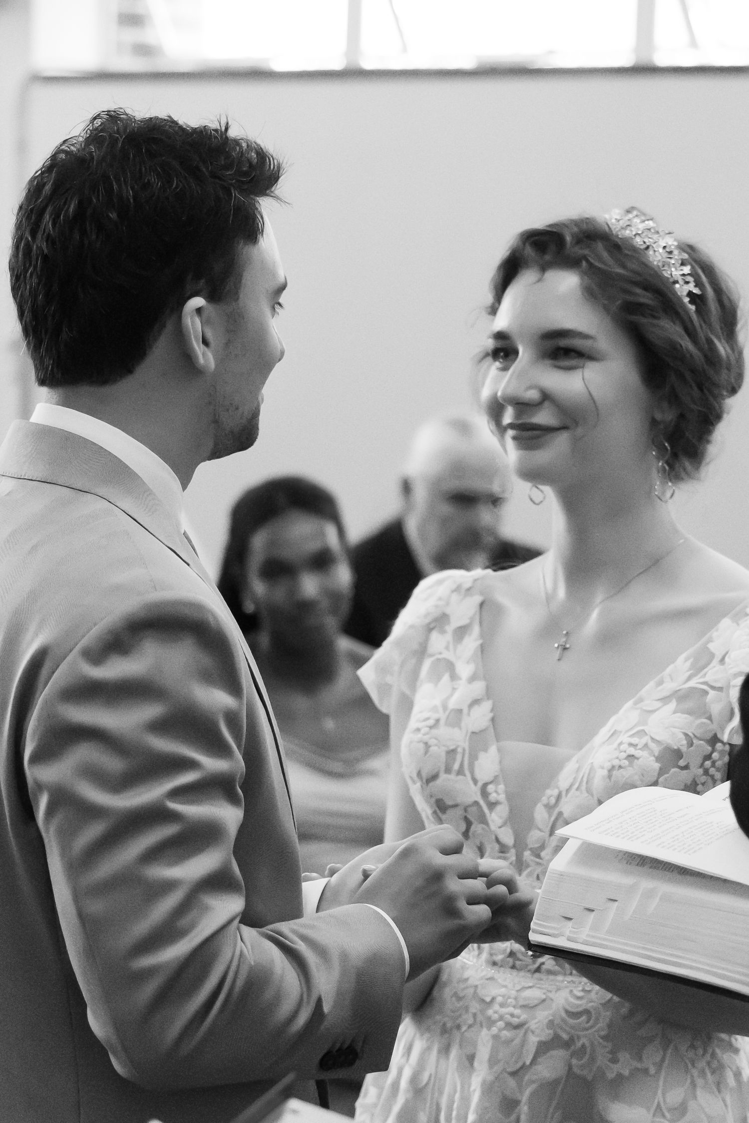 Black and white photo of bride and groom exchanging vows during their wedding ceremony