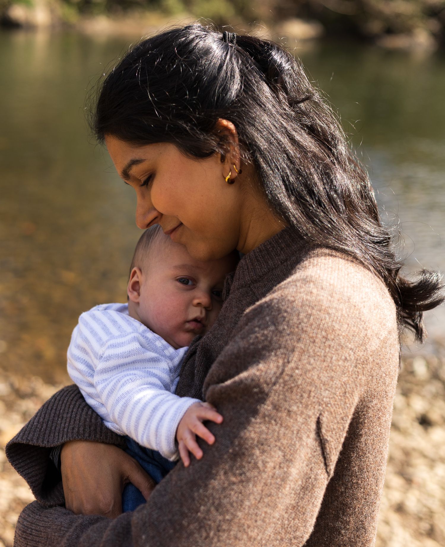 Mother holding her baby close by the riverside