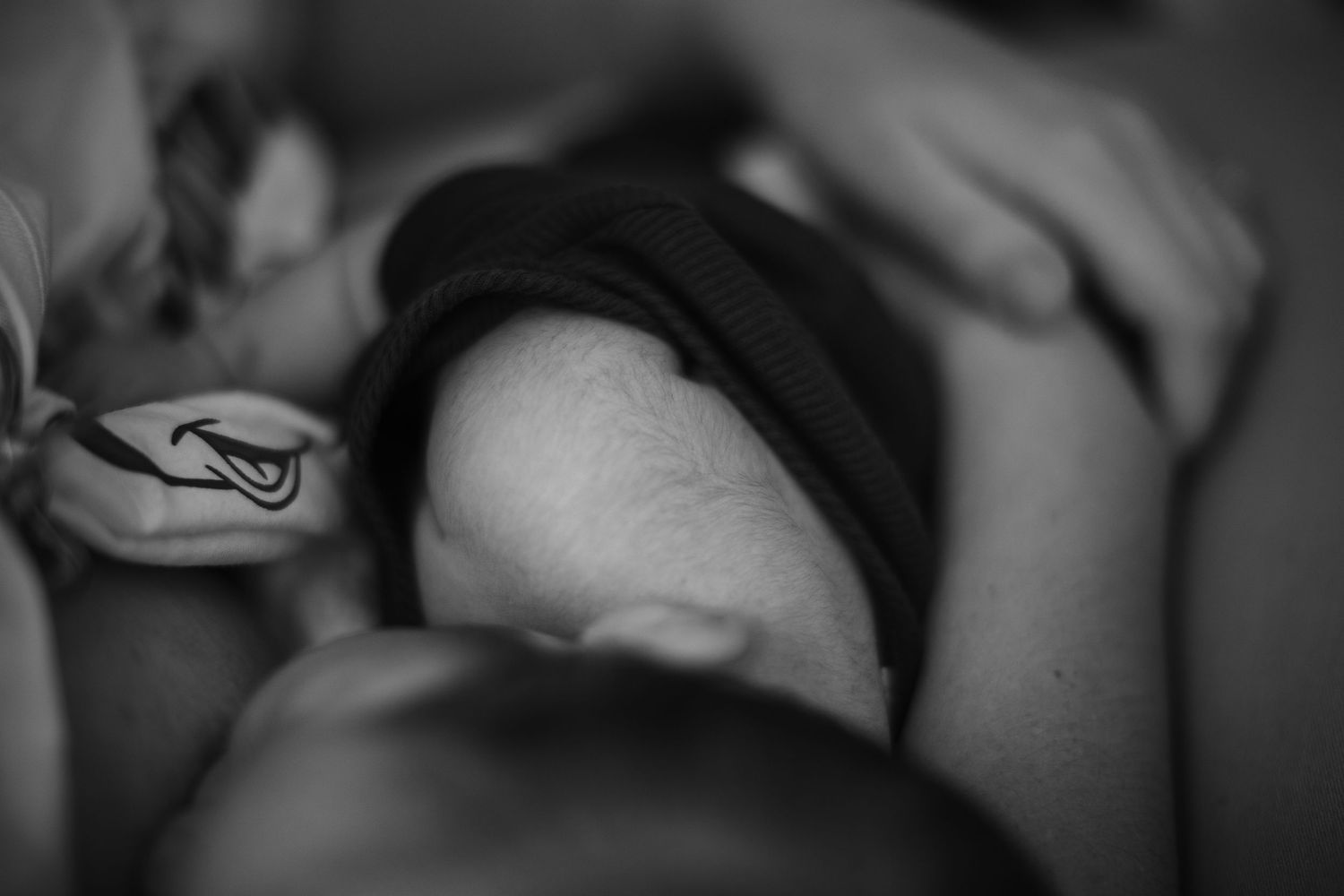 Black and white close-up photo of a newborn baby breastfeeding, capturing an intimate mother and child bonding moment.