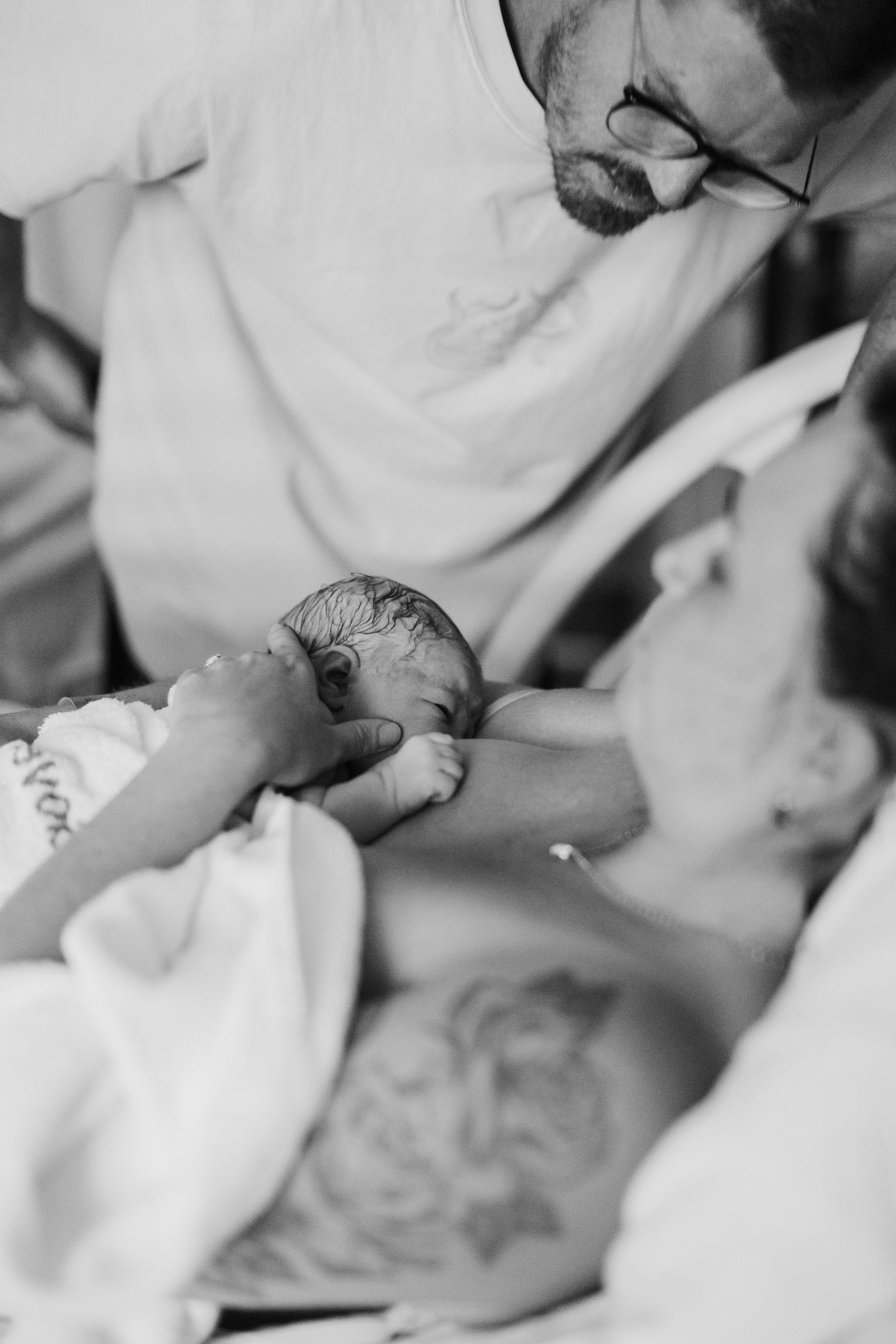 New parents tenderly holding their newborn baby after birth in black and white.