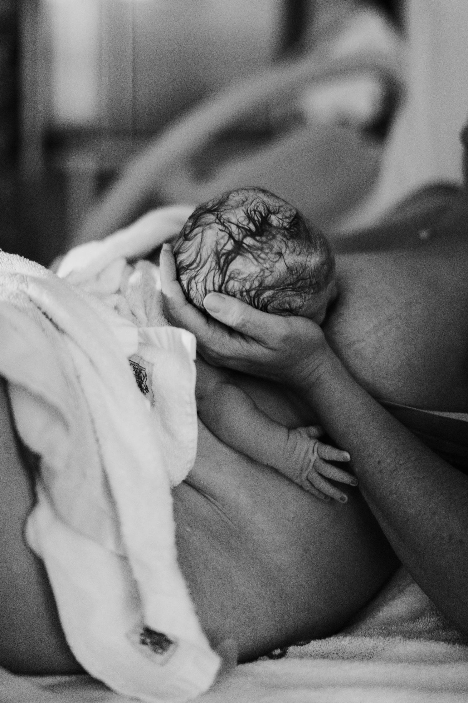 Black and white photo of a newborn baby being held by mother after birth.