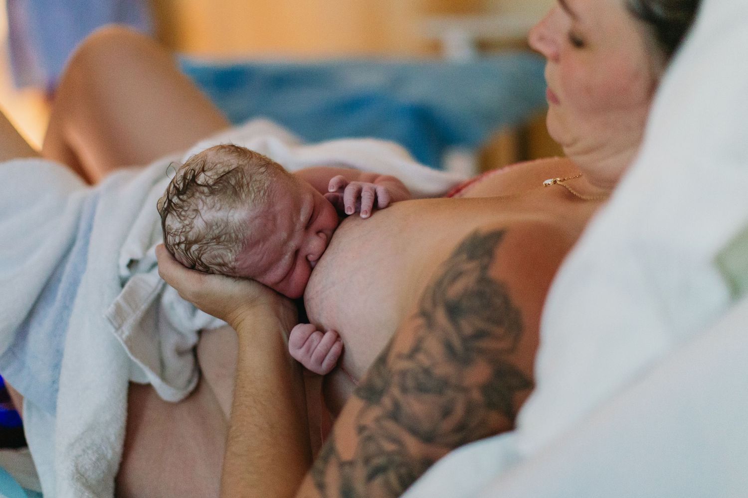 Mother holding her newborn baby immediately after birth in a hospital delivery room.