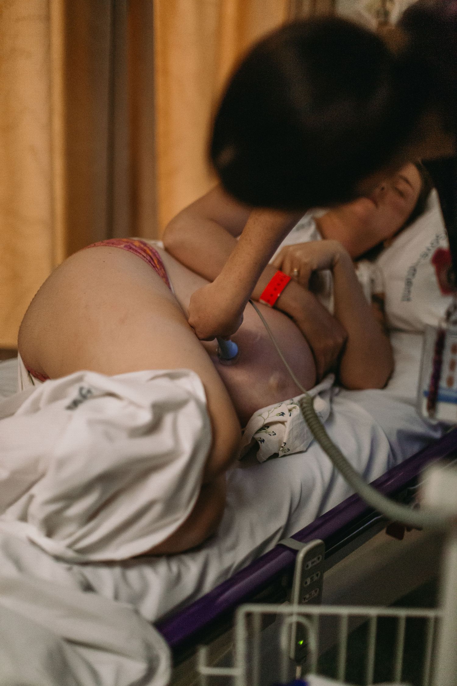 Pregnant woman lying on a hospital bed with fetal monitoring equipment attached during labor.