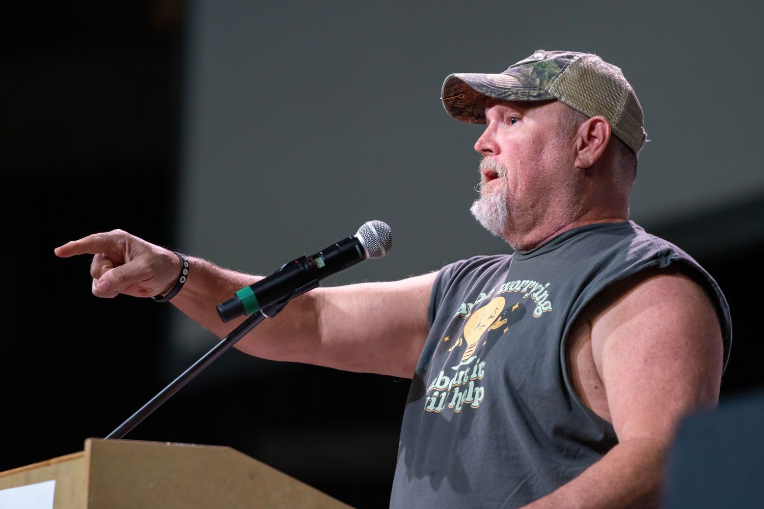 Man in sleeveless shirt speaks passionately at a podium while pointing at the audience.