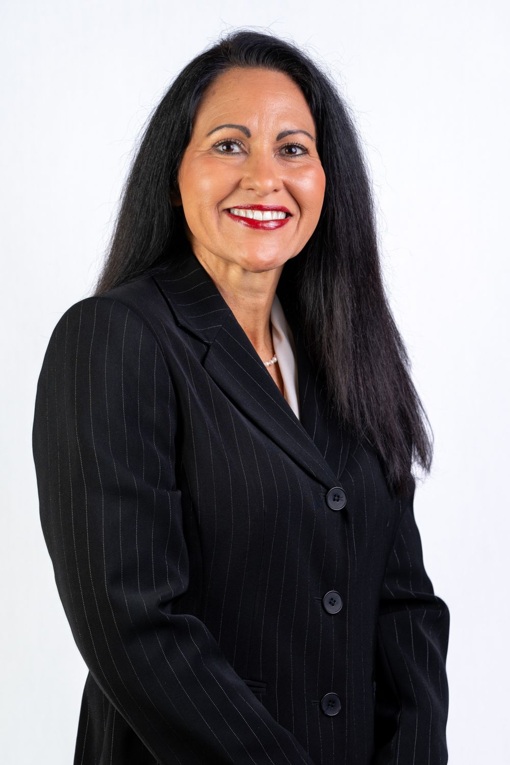 Professional woman in black pinstripe blazer with long dark hair smiling against white background.