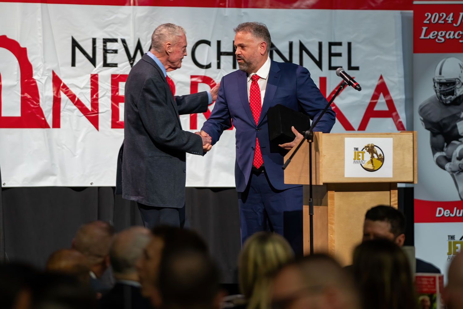 Tom Osborne and Matt Rhule shake hands on stage at the Jet Awards in 2024.
