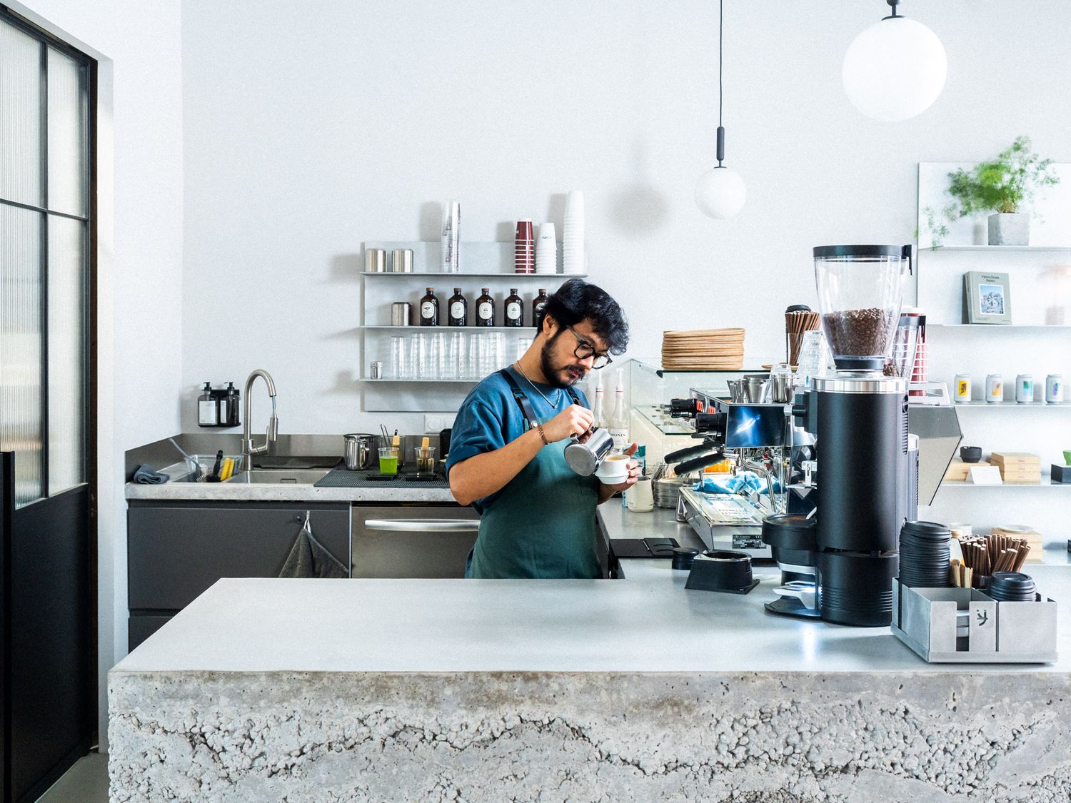 Nico an seinem Arbeitsplatz im Yuzu Cafe in Hannover, wie er einen Cappuccino zubereitet