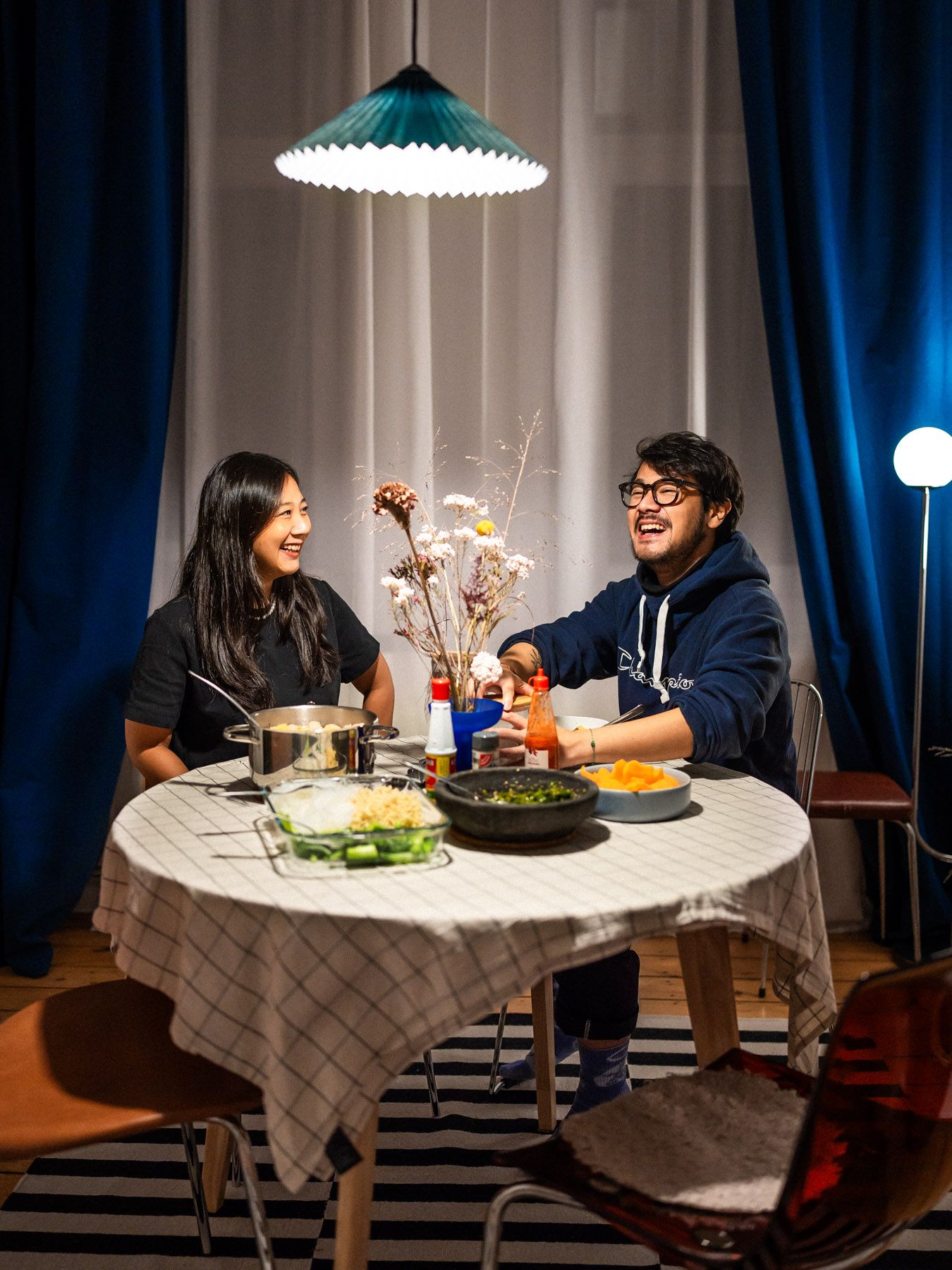 Nico sitzt lachend mit seiner Schwester Connie am Esstisch und isst zu Abend.