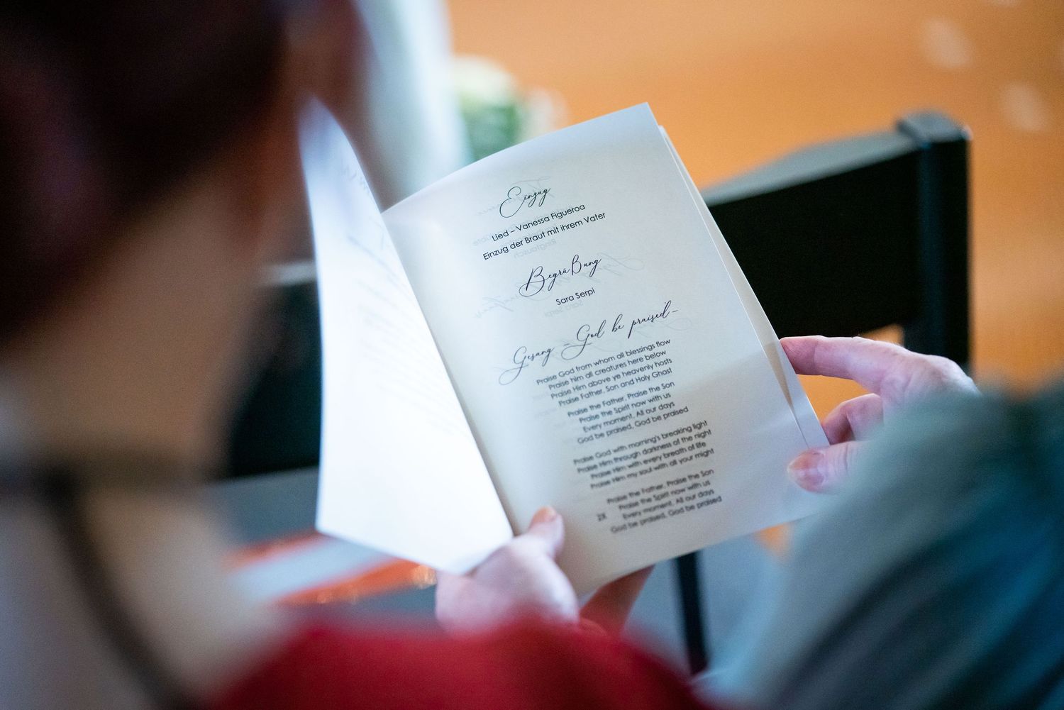 Gast hält während der Trauung die Willkommenskarte in der Hand in der St. Osdag Kirche bei Neustadt am Rübenberge