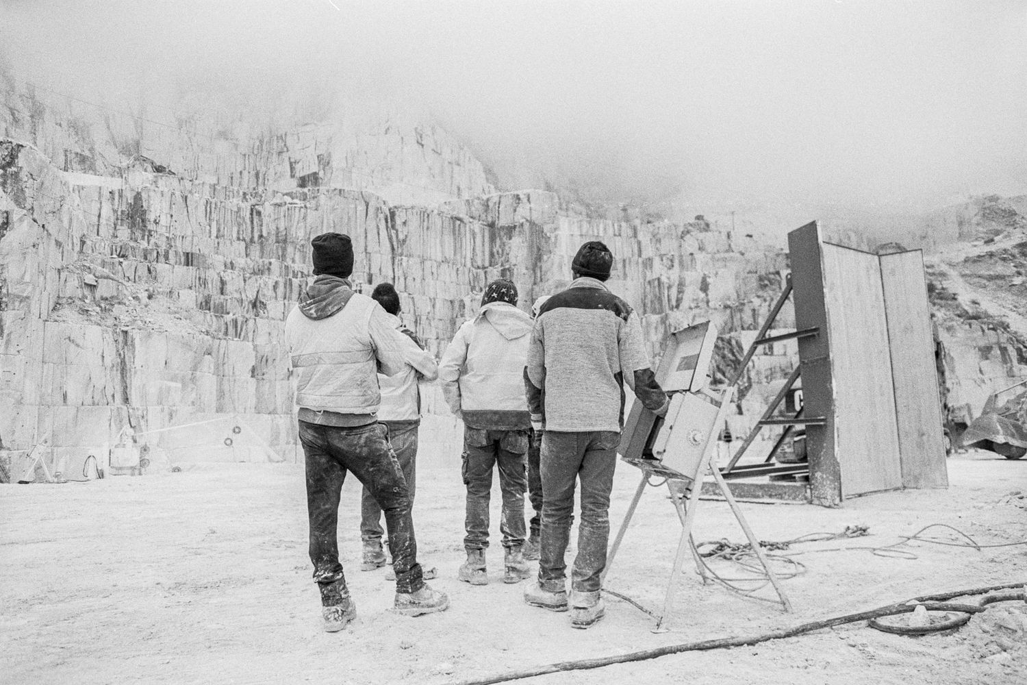 Vier Arbeiter überwachen eine Säge in einem Marmorsteinbruch im Frantiscritti Tal von Carrara, Italien