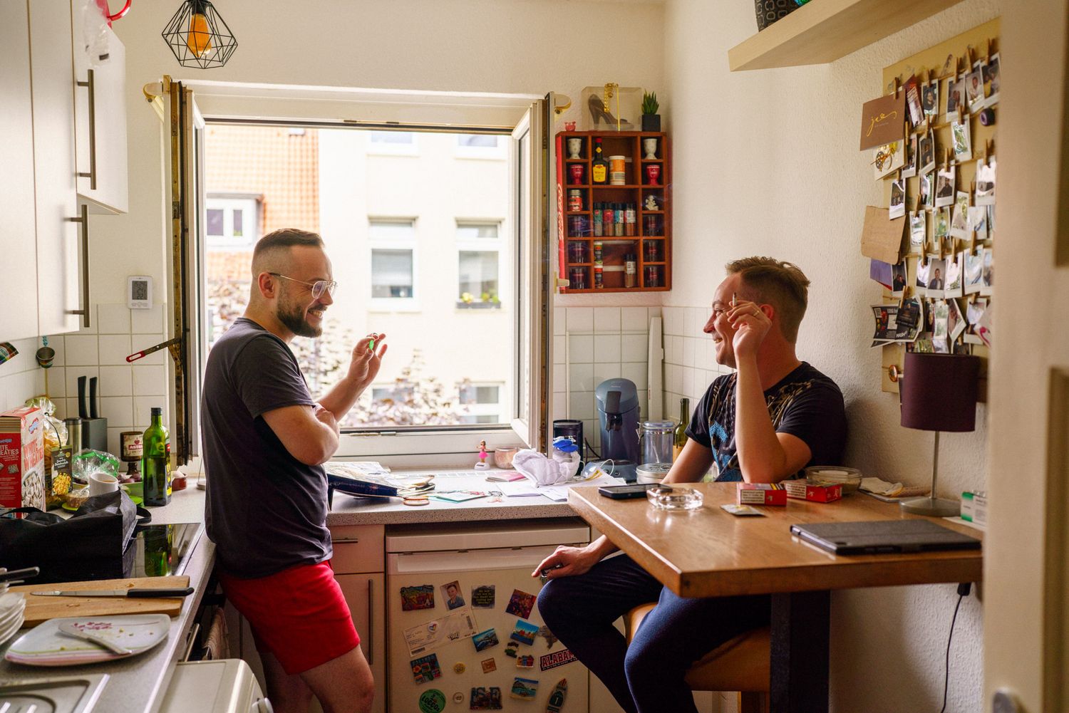 Christian und sein Ehemann Justin unterhalten sich und lachen bei einer Zigarette in der Küche der gemeinsamen Wohnung
