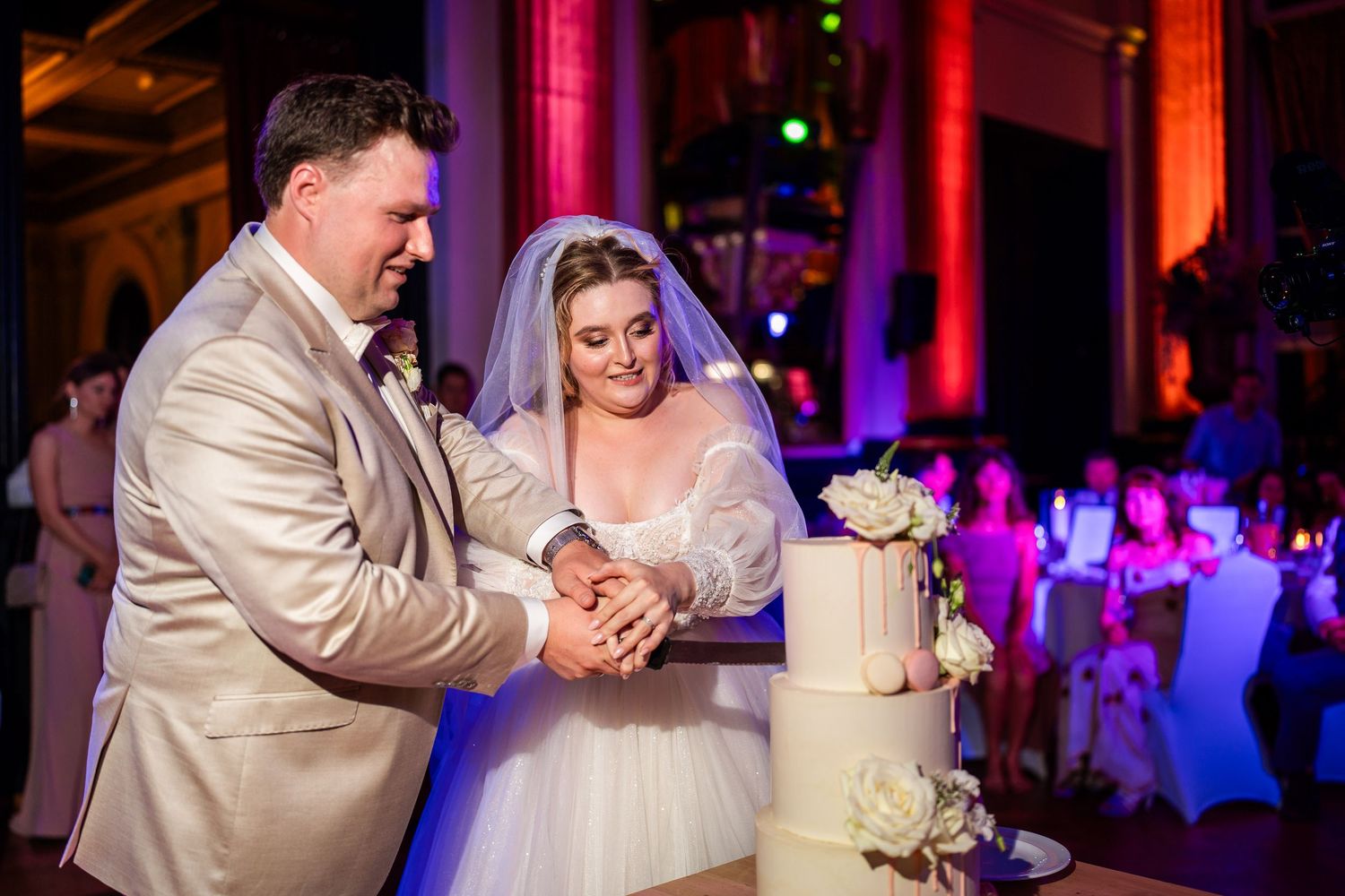 Das Brautpaar schneidet die Hochzeitstorte inmitten ihrer Gäste an