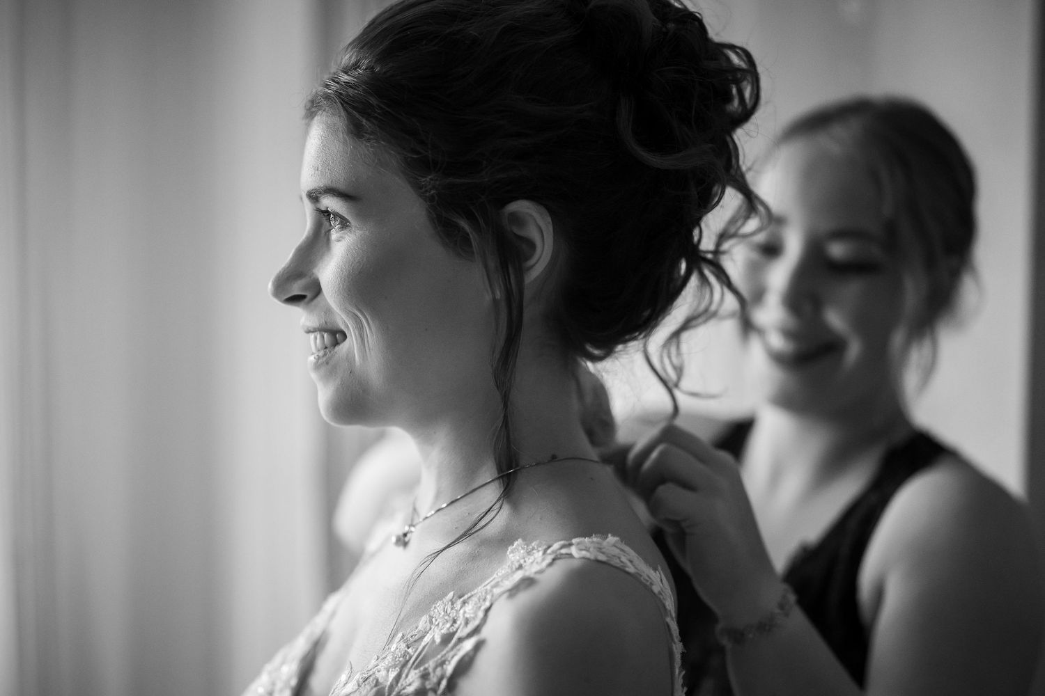 Die Trauzeugin schließt die Kette der Braut beim Getting Ready vor der Hochzeit