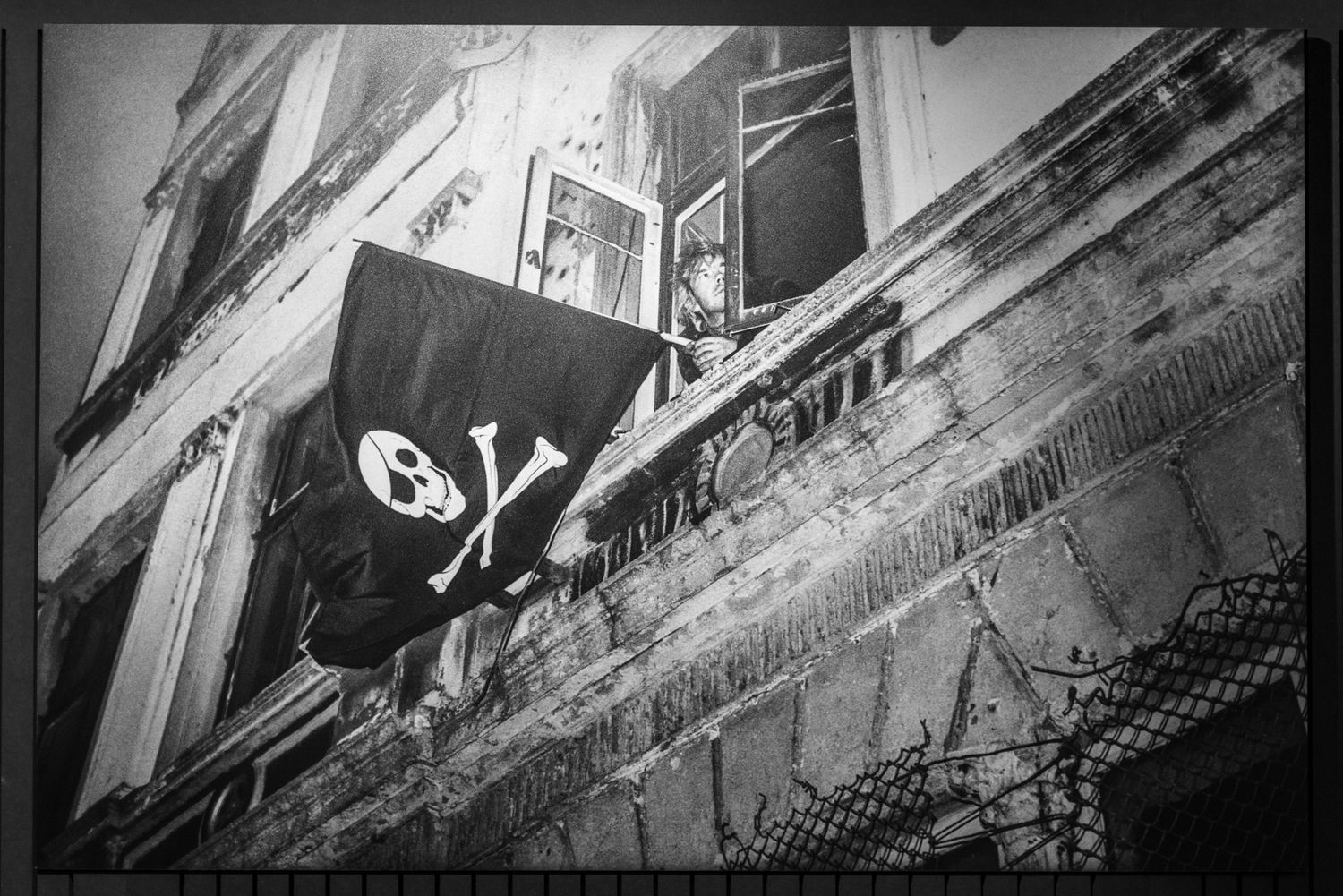Archivfoto zeigt Torsten Herrmann mit einer großen Totenkopfflagge aus dem Fenster eines besetzten Hauses in der Hafenstraße schauend