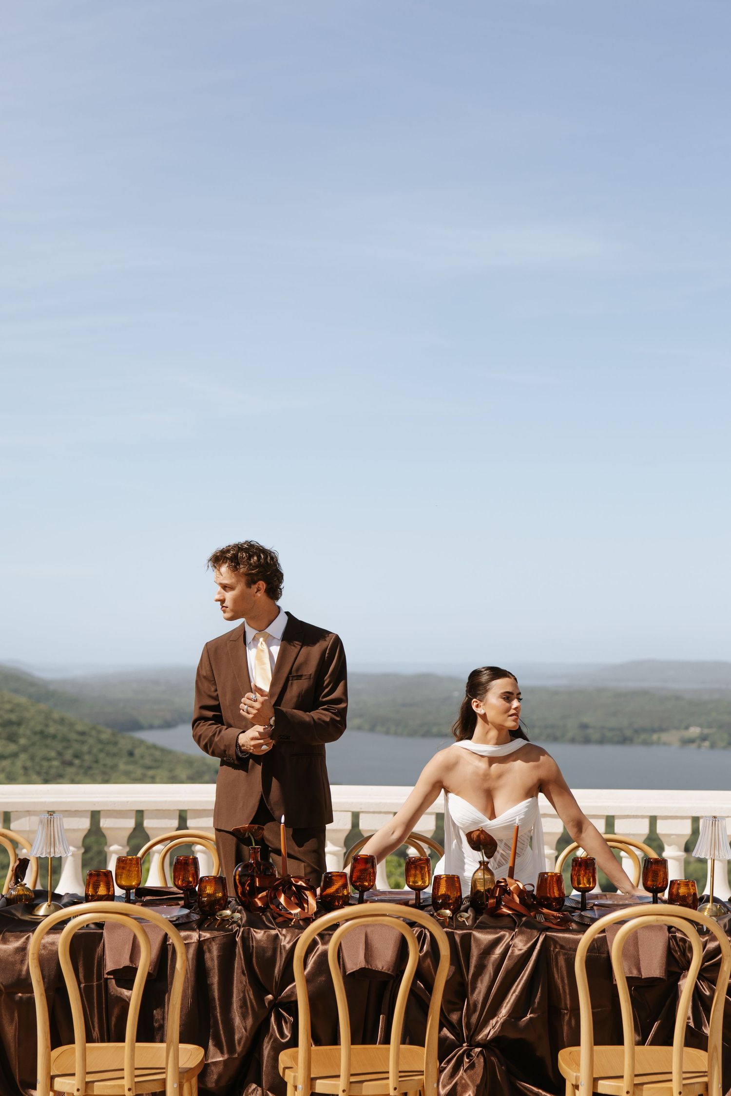 Bride and groom standing at elegantly decorated outdoor reception table with mountain view.