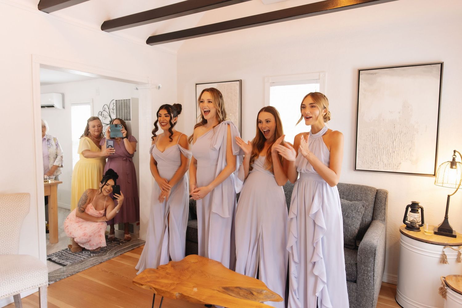 Bridesmaids in lavender gowns react with joy seeing bride for first time.