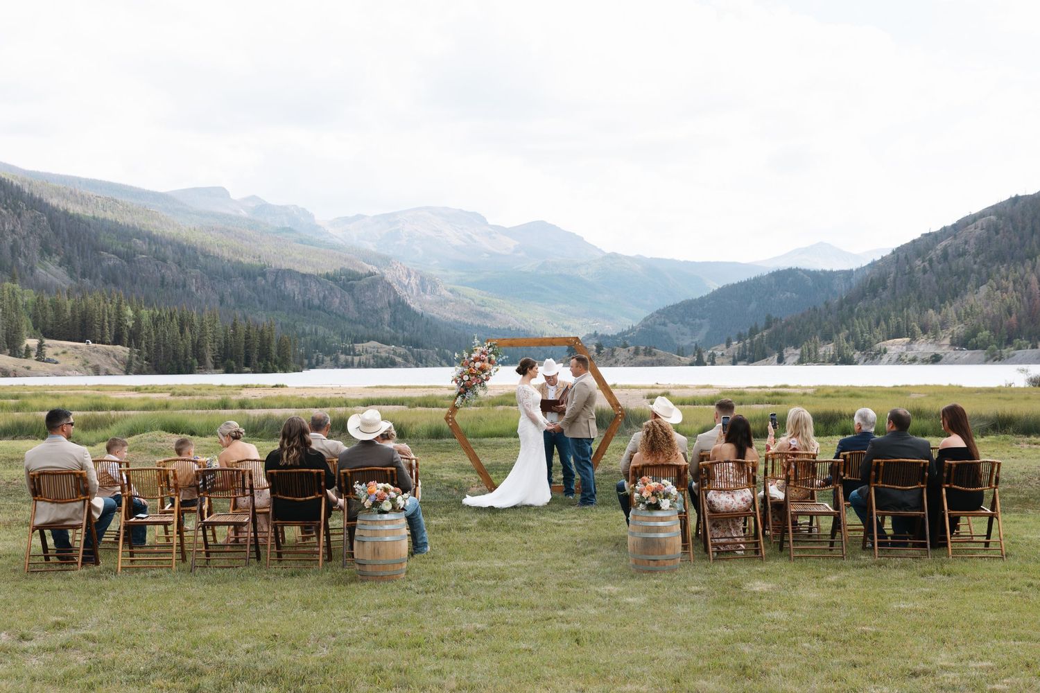 Outdoor mountain wedding ceremony with guests seated in a meadow beside a lake with stunning Rocky Mountain views. Lake City Colorado