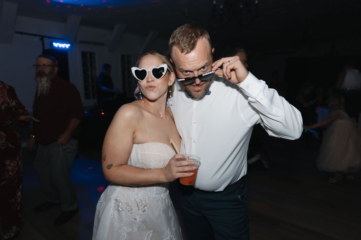 Bride and groom pose with fun sunglasses at wedding reception dance party.