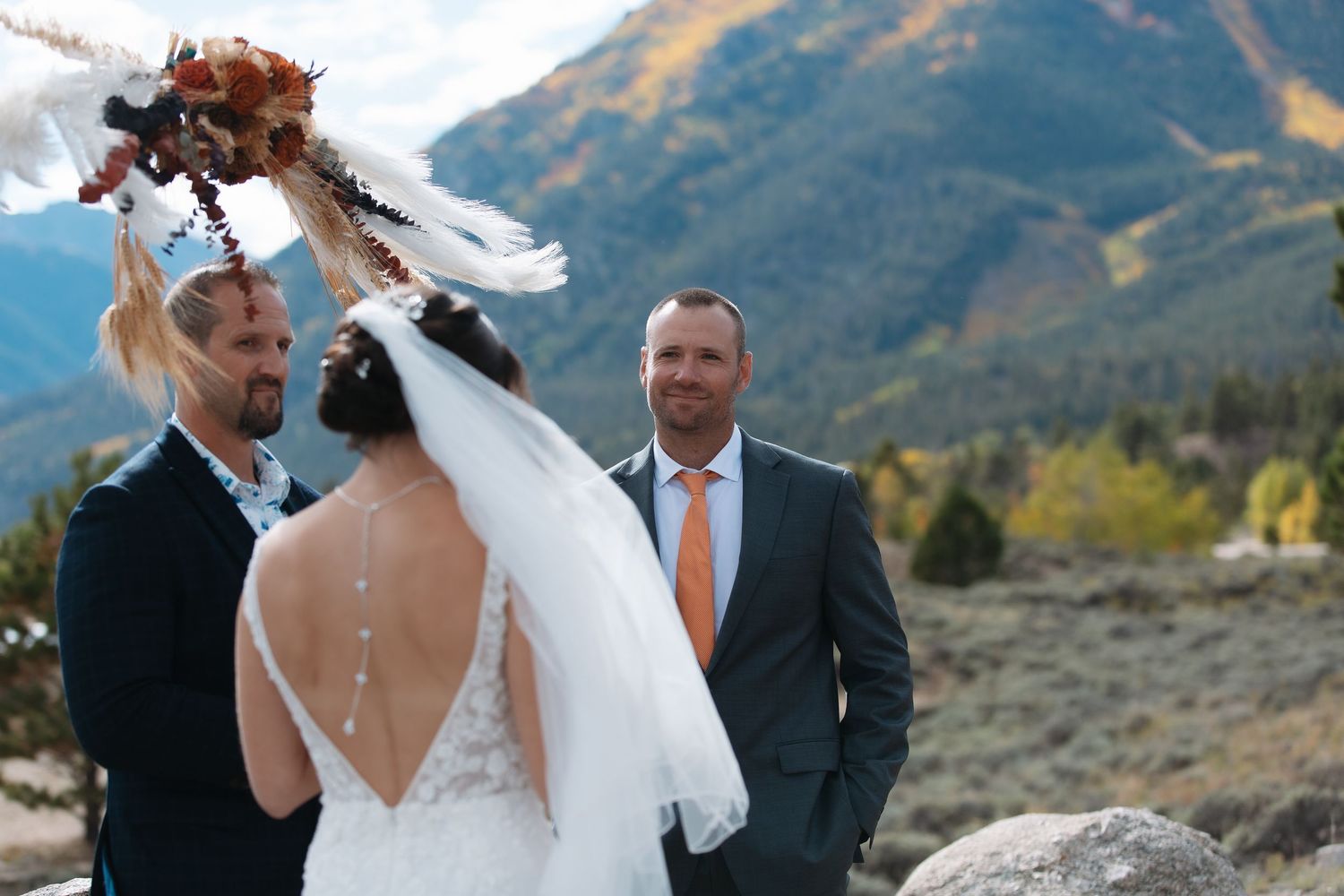 Bride and groom exchanging vows outdoors with stunning Rocky Mountain scenery in the background. Twin Lakes