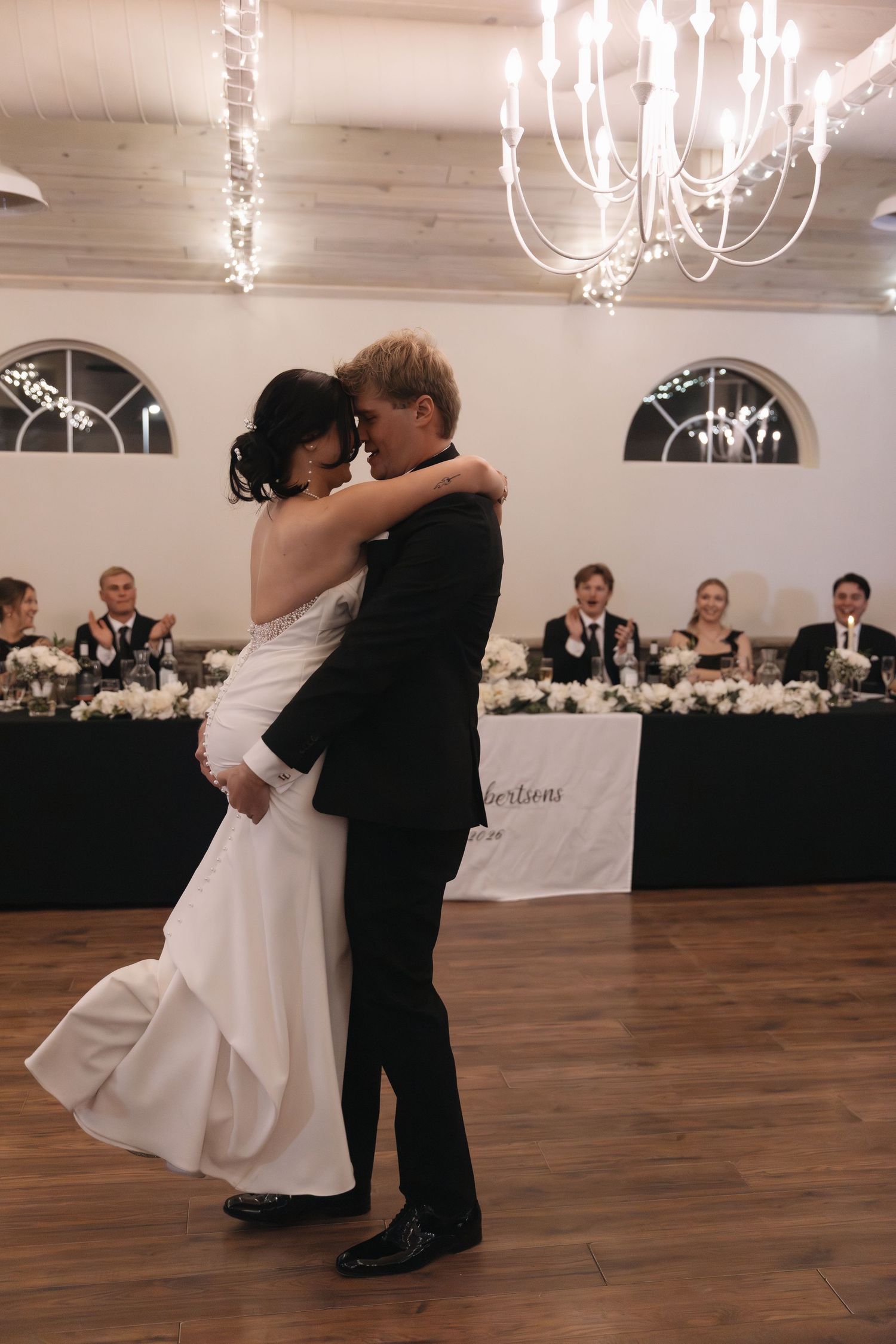 Bride and groom share their first dance under elegant chandeliers in a decorated wedding reception venue.