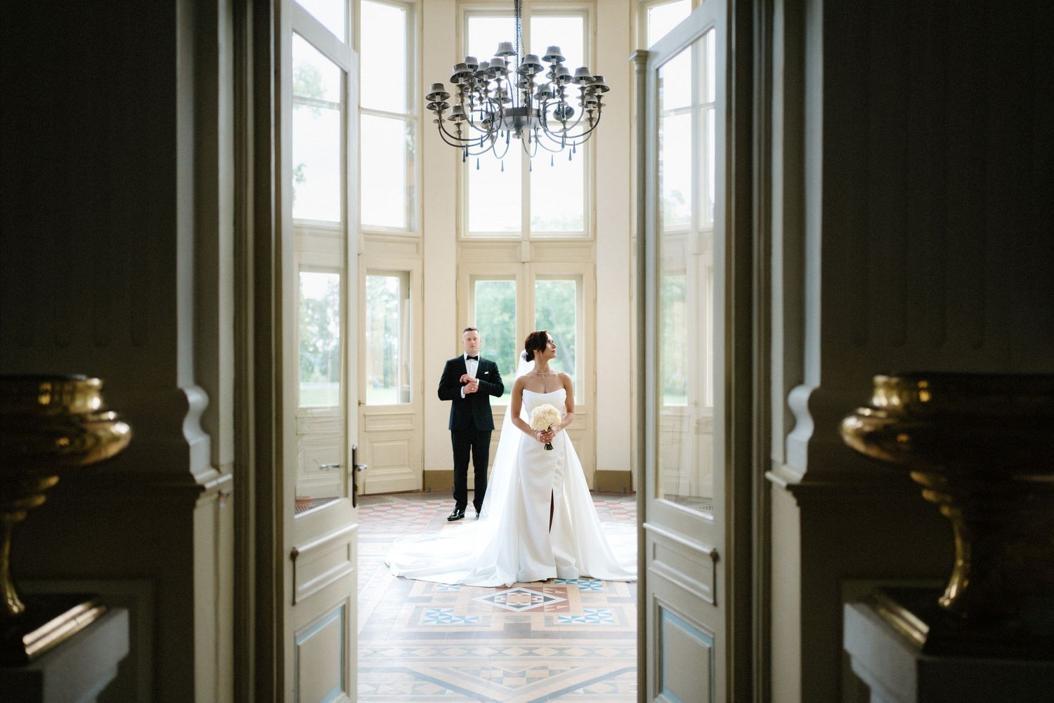 Elegant hallway with chandelier and large windows creating dramatic silhouettes.