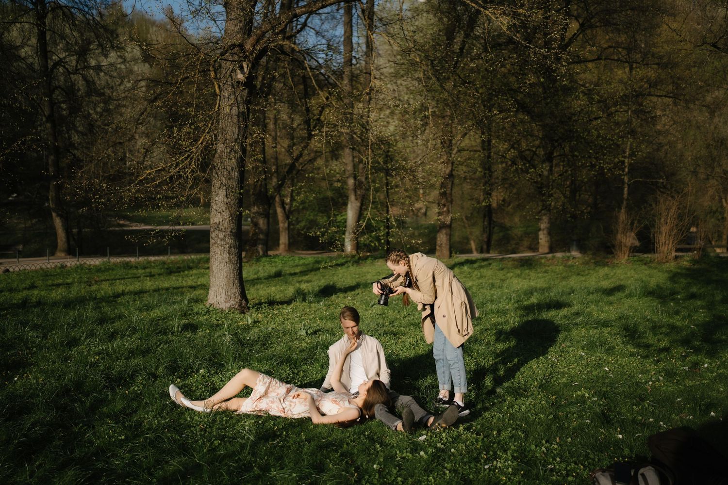 People relaxing on blankets in a sunny park with scattered trees.