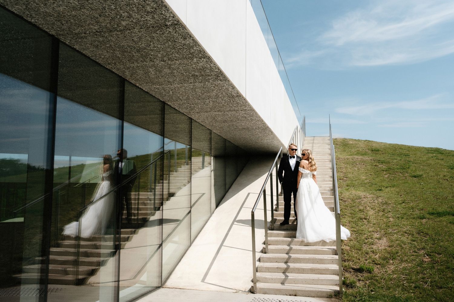 Modern architectural wedding venue with dramatic angular white walls against blue sky.