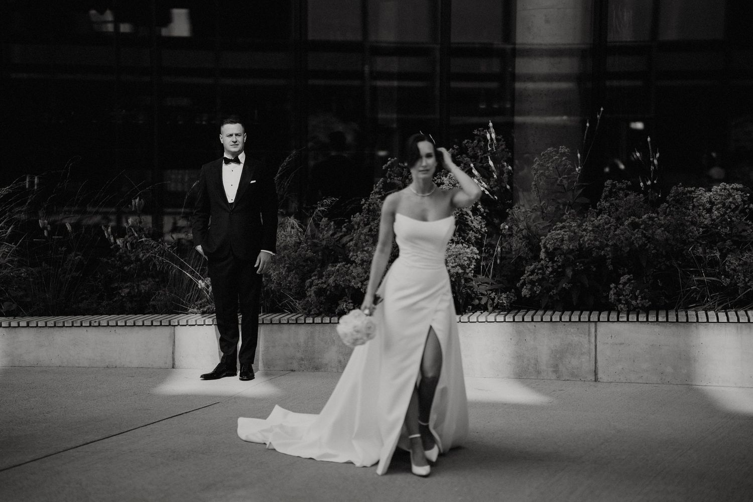 Black and white wedding photo with couple against urban architecture.
