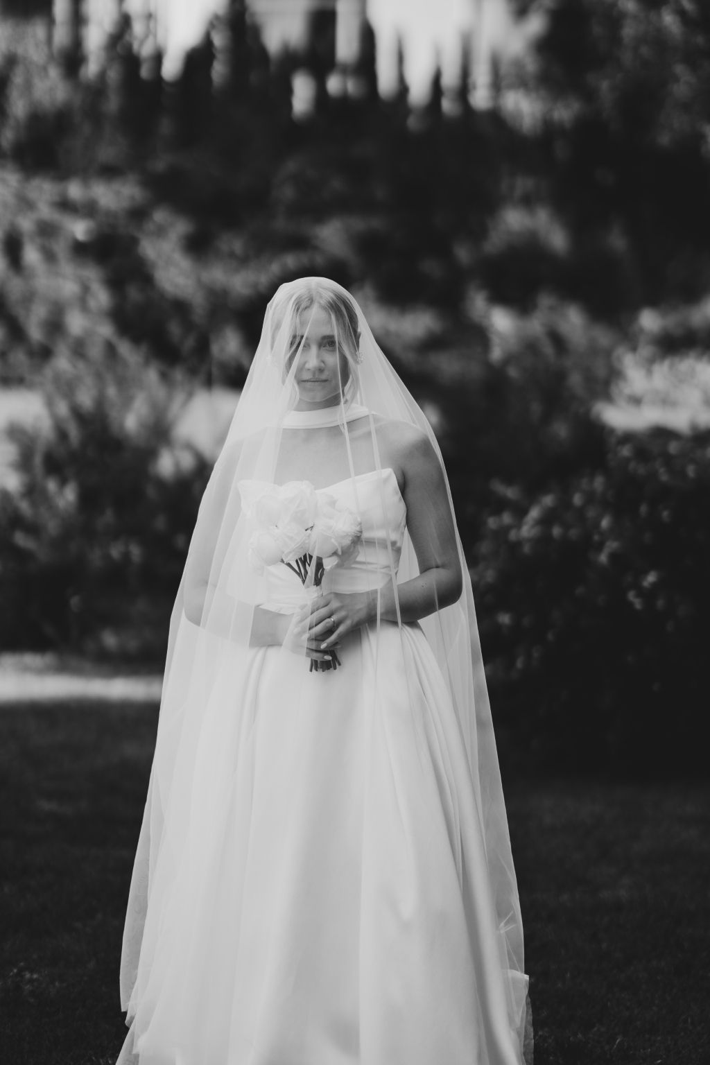 Ethereal bridal portrait with flowing veil against a dark background.