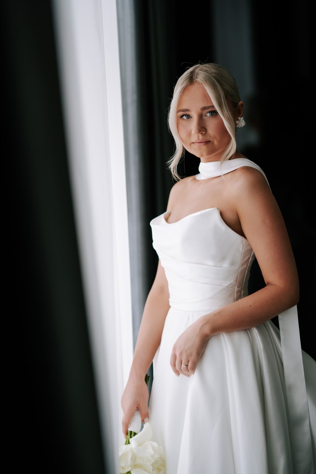 A series of elegant bridal portraits in white against a dark background with natural window light.