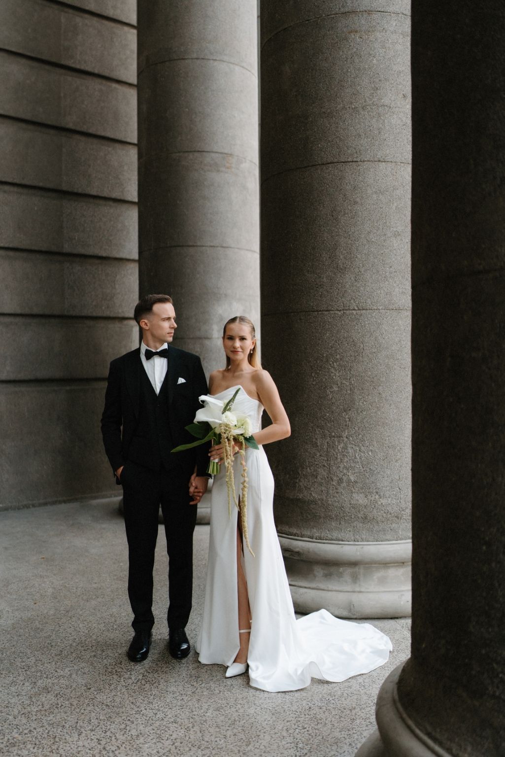 A formal wedding portrait against classical stone columns.