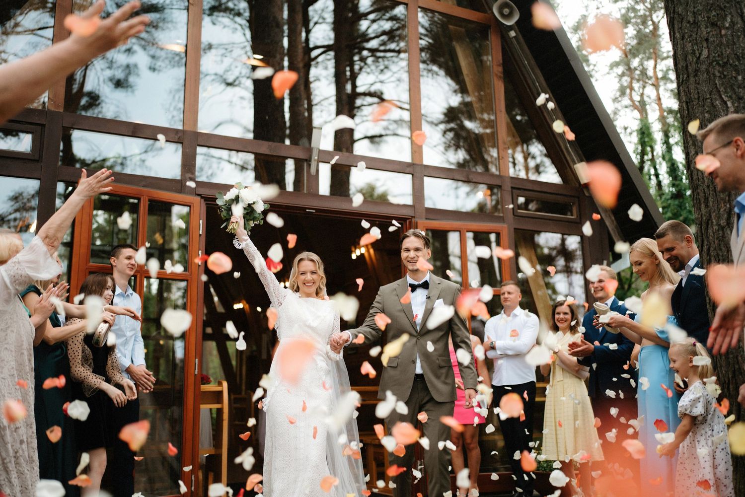 Wedding celebration with confetti being thrown at a rustic wooden venue with string lights.