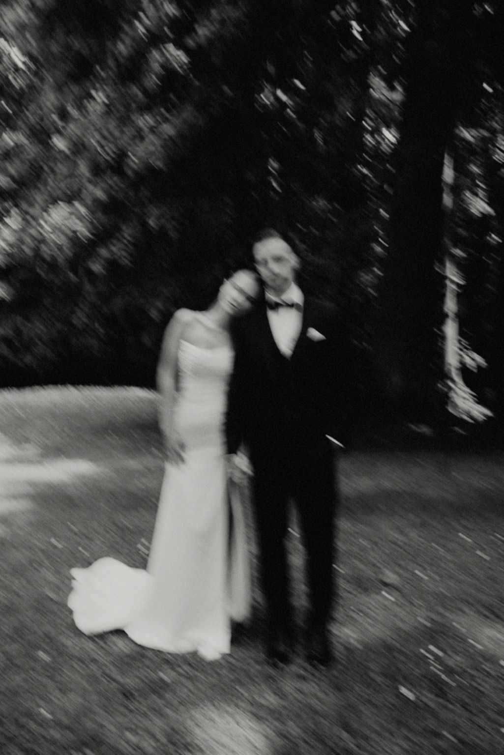 Artistic black and white portrait of a couple on their wedding day in a garden setting.