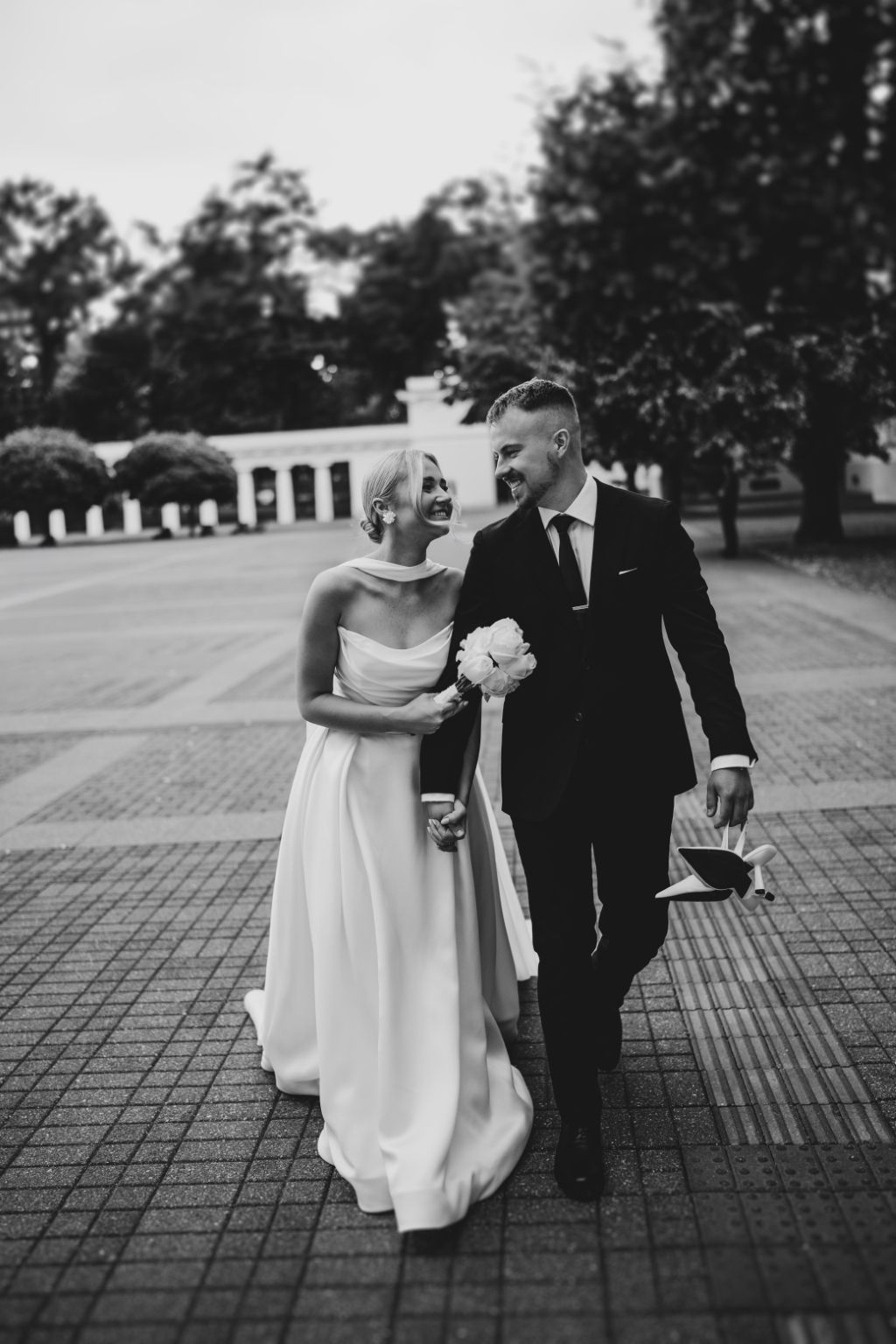 Black and white photo of couple walking on brick pavement during wedding.