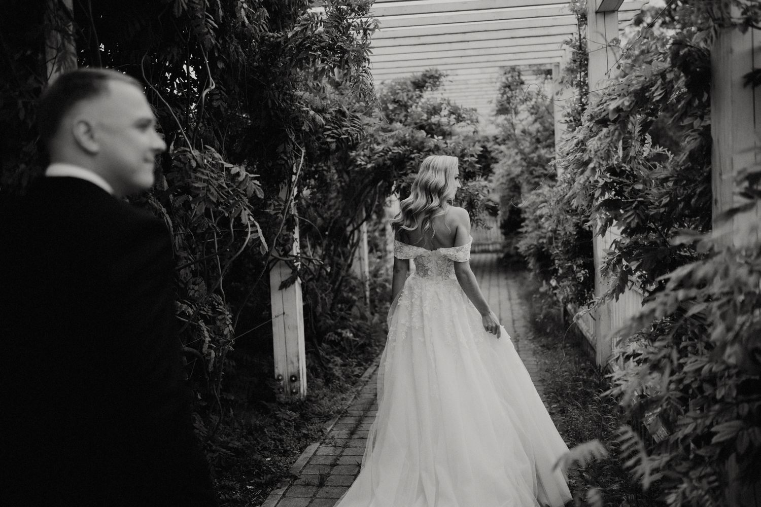 Garden pathway wedding photos with lush greenery and white architectural details.