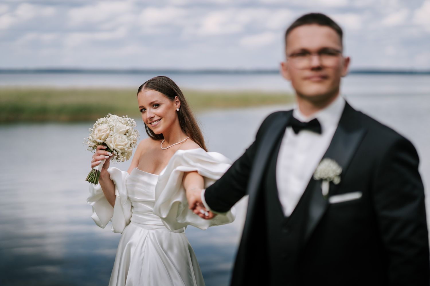 A waterfront wedding photoshoot with dramatic cloudy skies in the background.